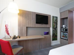 a hotel room with a desk and a tv on a wall at Novotel Lodz Centrum in Łódź +97 photos