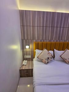 a bedroom with a bed with a wooden head board at Hotel Wellingten in Mumbai