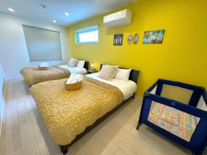 a bedroom with two beds and a yellow wall at Grandioso Onna 7-D - Vacation STAY 45335v in Atsutabaru +40 photos