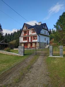 a large white house with a black roof at Krynica Zdrój - Dom nad wodą in Piorunka