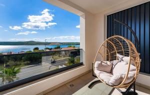 een rieten stoel op een balkon met uitzicht op het water bij Villa Sense in Posedarje