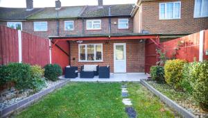 a house with a red fence and a patio at Windsor and Heathrow Stay Comfort & Free Parking in Slough
