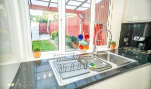 a kitchen sink with a dish drying rack next to a window at Windsor and Heathrow Stay Comfort & Free Parking in Slough