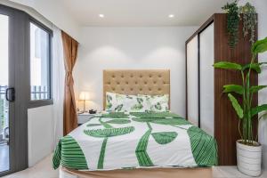 a bedroom with a bed with a green and white comforter at Dominiks Comfort and silent Studio Tambuli Balcony Pool Mactan Ocean View High Floor in Lapu Lapu City