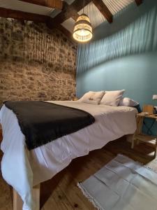 a bed in a room with a brick wall at La aldea de lug in Rozagás +3 photos