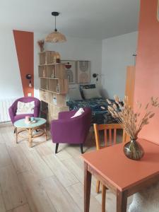 Una sala de estar con un sofá y sillas morados. en Chalet bain nordique - Calm & relax, en Bellême