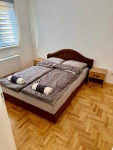 een slaapkamer met een bed en een houten vloer bij Romansa in Bijeljina