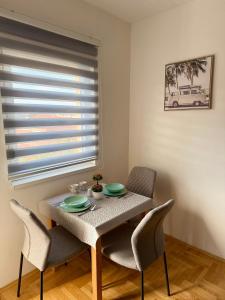een eettafel en stoelen in een kamer met een raam bij Romansa in Bijeljina +6 foto's