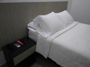 辛塞莱霍Hotel Boutique Santorini Class的一张带白色床单和枕头的床,旁边是桌子