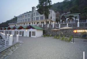 un edificio con sillas y sombrillas frente a un edificio en Aesquire Hotel, en Bhimtal