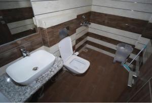 Un baño con un lavabo blanco y un inodoro. en Aesquire Hotel, en Bhimtal
