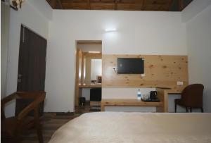 Un dormitorio con un escritorio y un televisor en la pared. en Aesquire Hotel, en Bhimtal