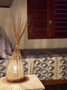 a vase with grass in it on a table with a bed at Casa velha in Amontada