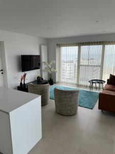 a living room with a couch and chairs and a table at Spacious and modern apartment with open sea view in Ostend