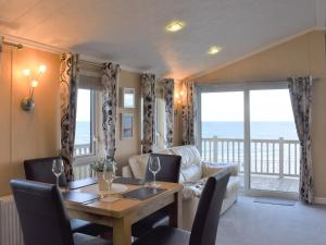 LlanddulasにあるSunset Lodgeの眺めの良いテーブルとソファのあるダイニングルーム