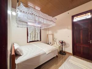 a bedroom with a white bed and a window at A Tứng House Bản Giốc in Trùng Khánh