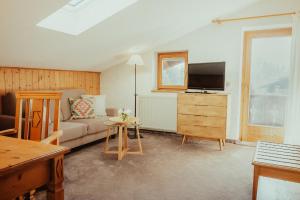 a living room with a couch and a tv at Seehotel Malerwinkel in Rottach-Egern