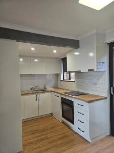 a kitchen with white cabinets and a stove top oven at 2 bedroom 2 level Apartment - Hydra Holiday Unit 6 in Merimbula
