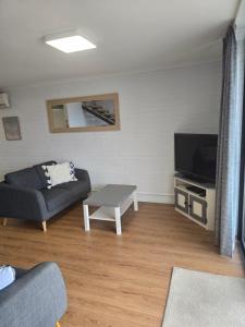 ein Wohnzimmer mit Sofa und Fernseher in der Unterkunft Hydra 2 bedroom Holiday Unit in Merimbula