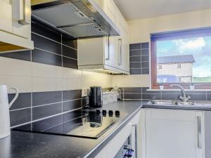 a kitchen with white cabinets and a sink and a window at The Barn in Lagg