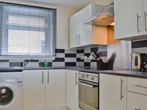 a kitchen with white cabinets and black and white tiles at Seaview in Oban