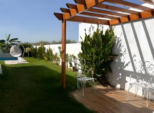 une terrasse en bois avec des chaises et une pergola dans l'établissement Villa Bianca, à Sidi Jedidi