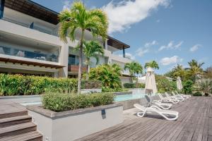 Una imagen de una villa con sillas y piscina. en Beachfront apartment with exceptional lagoon view, en Grand Baie