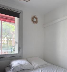 ein Schlafzimmer mit einem Bett neben einem Fenster in der Unterkunft Studio cv 4p, parking privée cosy design in La Grande-Motte