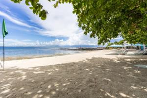 a sandy beach with a pier and the ocean at Dominiks Comfort and silent Studio Tambuli Balcony Pool Mactan Ocean View High Floor in Lapu Lapu City