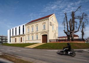 Ein Mann, der vor einem Gebäude Motorrad fährt. in der Unterkunft Heritage Hotel Knopp in Novska