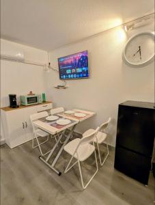eine Küche mit Tisch, Stühlen und einer Uhr in der Unterkunft Studio cv 4p, parking privée cosy design in La Grande-Motte