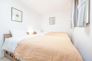 a white bedroom with a bed and a window at Skytree House Oshiage New 3-story Villa, 2 Showers, 2 Toilets, 4 Rooms, 3 min walk to Oshiage Station in Tokyo