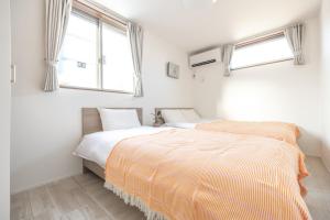 two beds in a bedroom with two windows at Skytree House Oshiage New 3-story Villa, 2 Showers, 2 Toilets, 4 Rooms, 3 min walk to Oshiage Station in Tokyo