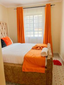a bedroom with a bed with orange curtains and a window at Naka homes in Lanet