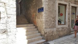 a woman standing next to a brick building with stairs at Apartment & room Ivan in Šibenik
