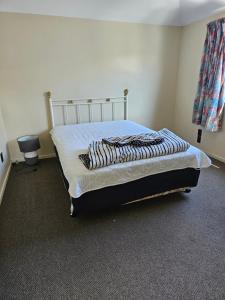 a bedroom with a bed with a white bedspread and a chair at Chriatcurrch Best Home in Christchurch