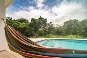 a hammock sitting next to a swimming pool at Nica Nest 3Br Eco Home Escamequita, NI in San Juan del Sur