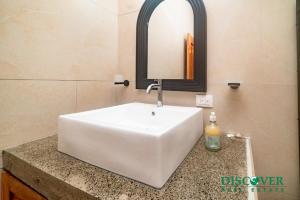 un lavabo blanc dans une salle de bain avec un miroir dans l'établissement Nica Nest 3Br Eco Home Escamequita, NI, à San Juan del Sur 22 autres photos