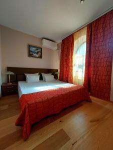 a bedroom with a bed with a red blanket and a window at Family Art Hotel Gallery in Pleven