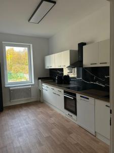 a kitchen with white cabinets and a large window at Apartmán 28 in Horní Město