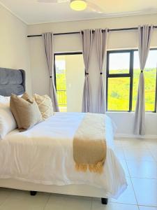 a bedroom with a large white bed with windows at 832 Villa in Ballito