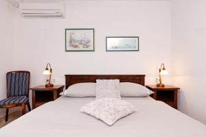 a bedroom with a white bed with two lamps and two chairs at Villa Maja in Bol