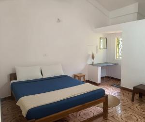 a bedroom with a blue bed and a desk at Rudresh Guest House in Arambol