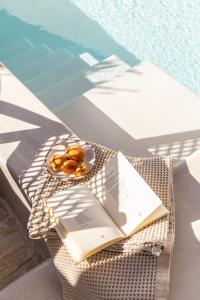 a book and a plate of food on a table next to a pool at Solus Suites Milos in Adamas