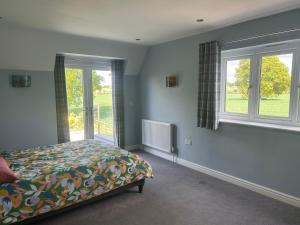a bedroom with a bed and two windows at Bumble cottage in Albrighton