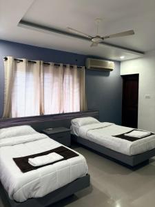 a bedroom with two beds and a ceiling fan at Zarica Homestay in Kannur