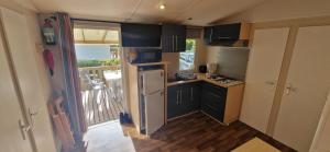 Una cocina con gabinetes negros y un refrigerador blanco. en Mobil-home de Ludo, en Ivry-la-Bataille
