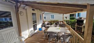 a patio with a table and chairs on a deck at Mobil-home avec grande terrasse in Ivry-la-Bataille