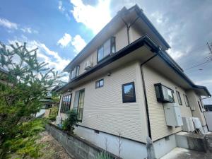 Una casa blanca con ventanas en un lateral. en 富士view 5LDK 河口湖駅まで徒歩圏内 最大10名で一棟貸し, en Fujikawaguchiko