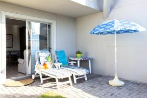 a patio with two chairs and an umbrella at Sand Castle in Langebaan +1 photo